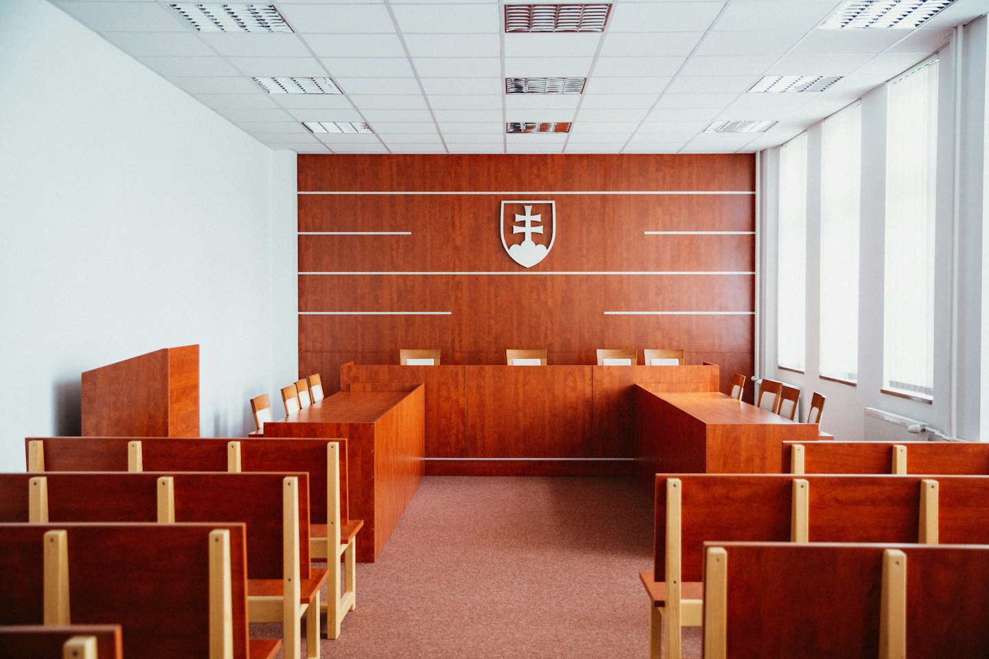 Sala de tribunal vacía con el estrado del juez y asientos de madera.